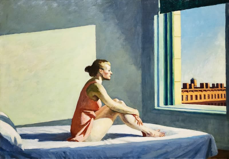 Donna seduta sul letto riflette guardando la finestra mentre la luce del mattino la illumina. - Lunedì -